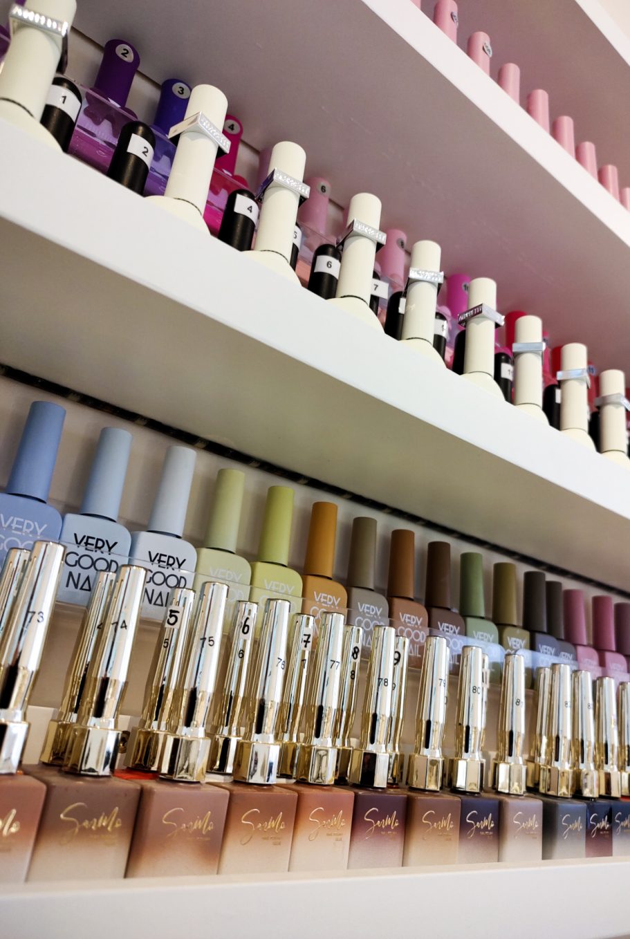 Kleurrijke nagellakflessen op planken in een nagelsalon.