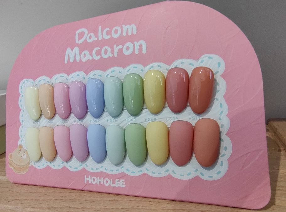 Kleurige macarons in pastelkleuren op een roze achtergrond, mooi gepresenteerd in rijen.